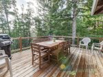 Back deck with gas BBQ, table and chairs. View of trees. 